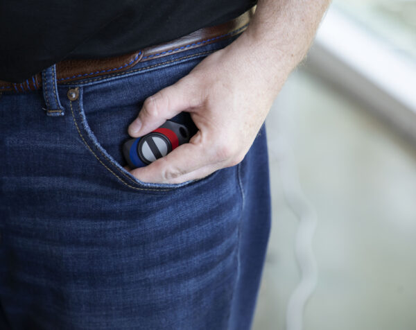 Image of someone holding the wireless panic button in their hand and putting it in their pocket